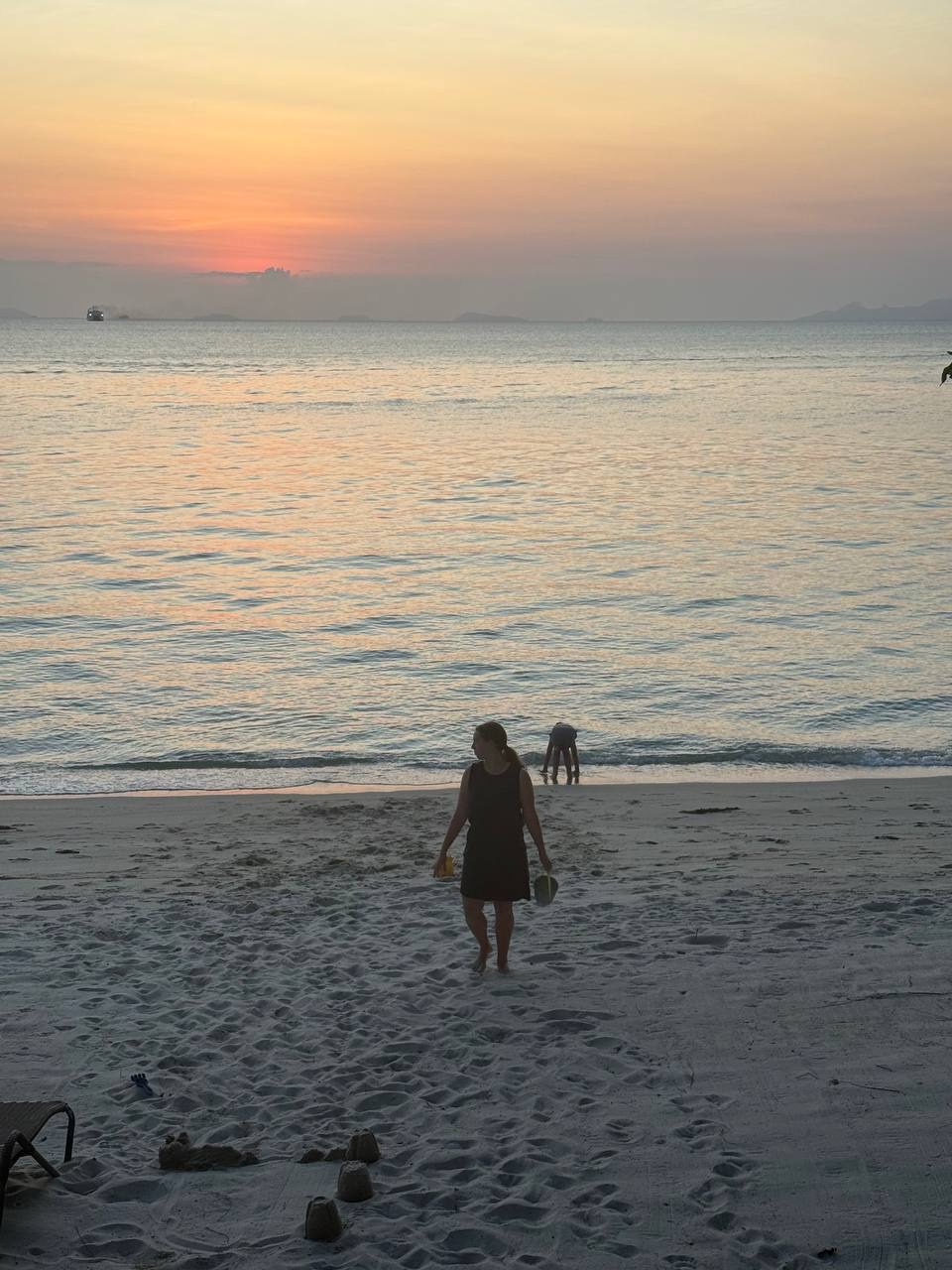 Silhouette of a person walking on the beach at sunset